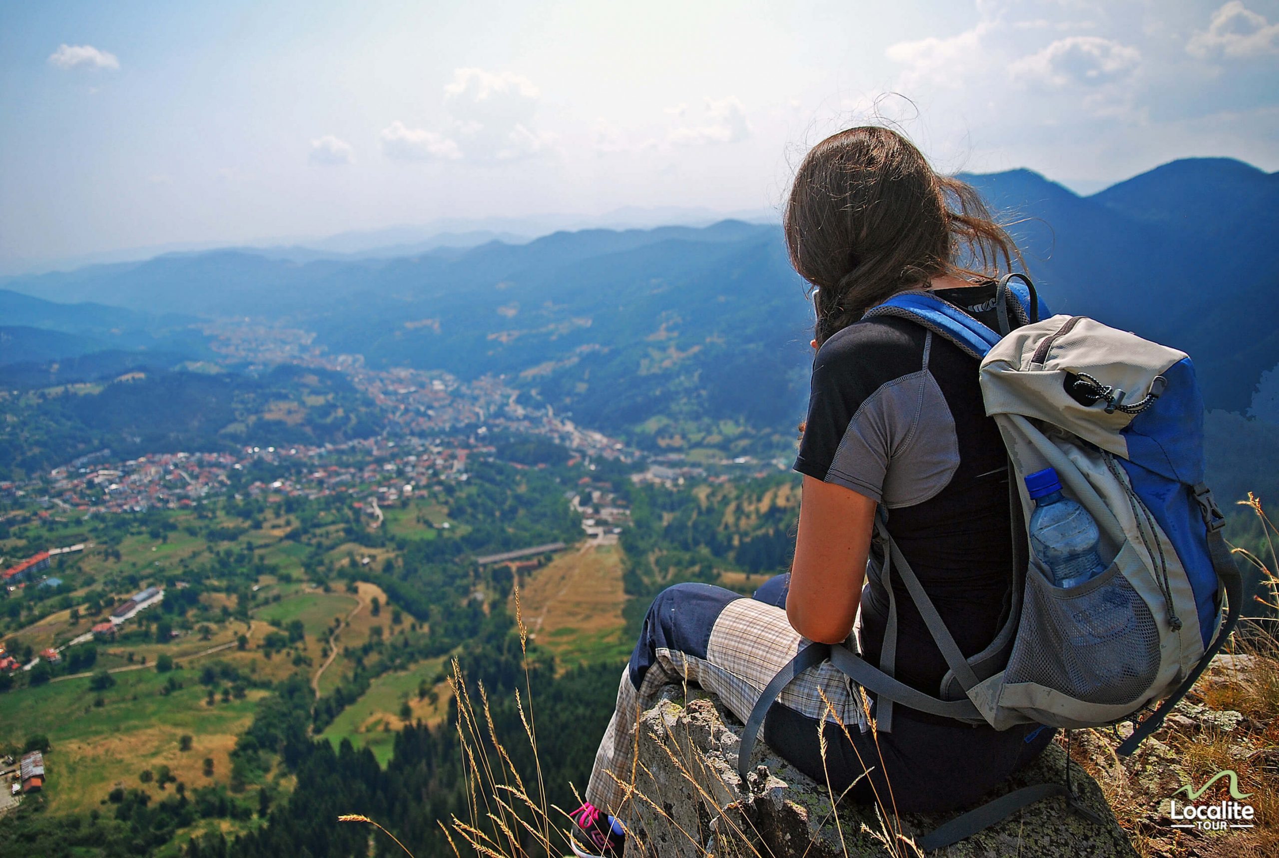 Girl in hiking outfit sitting on a rock enjoying the view in Rhodope mountains